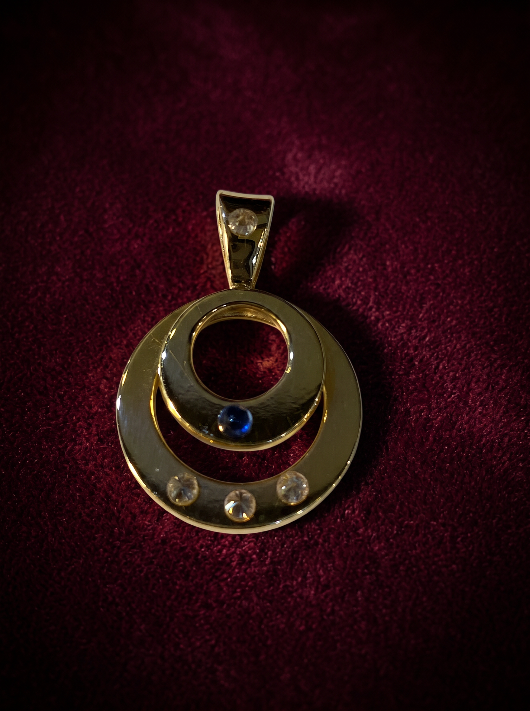 A gold double-circle pendant set with a sapphire and diamonds, made at our bench